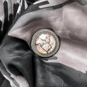 Dena Lyons silver magnetic scarf pin featuring original marble-inspired artwork beneath beveled crystal, elegantly securing a black and blush patterned scarf.